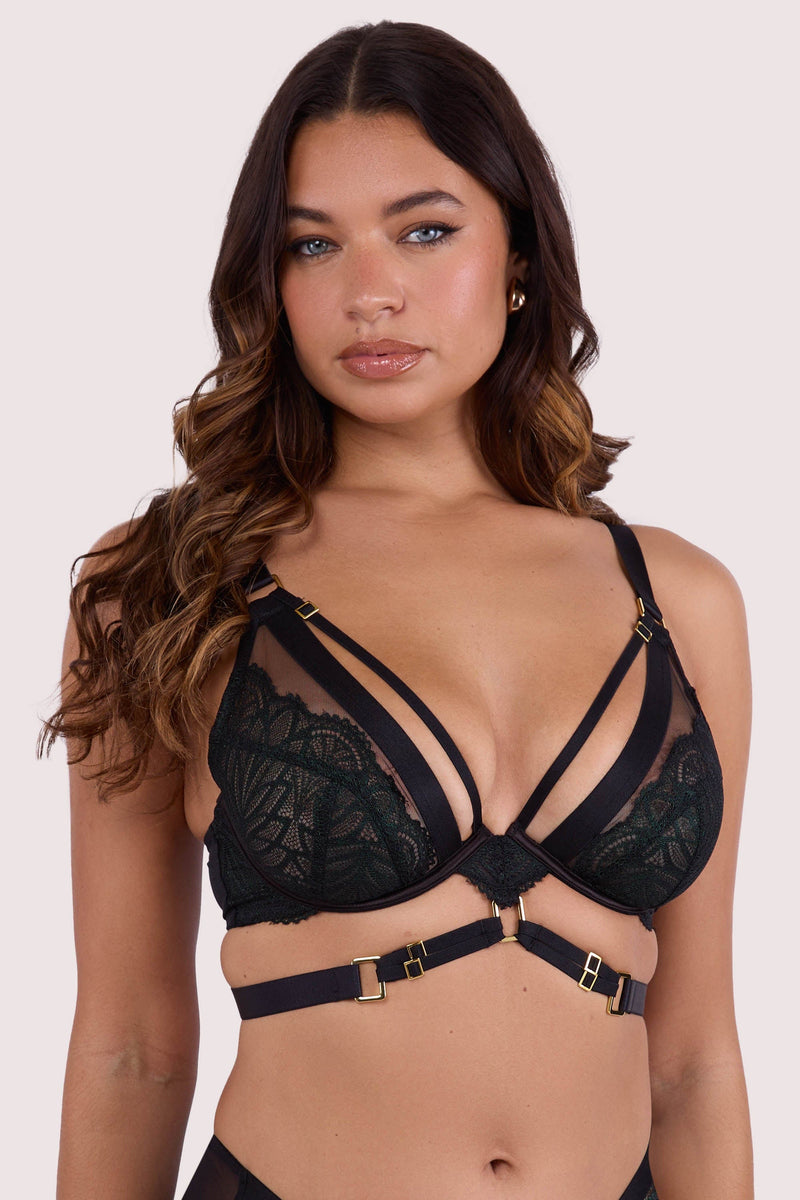 Model wears dark green wet-look  plunge bra with  underwire cups, strappy harness design, and gold buckle detailing
