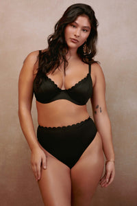 model wears black scalloped underwire bikini top and high waist bottoms swimwear set