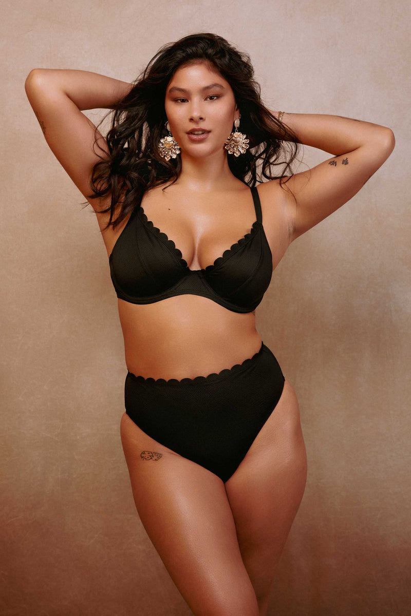 model wears black scalloped underwire bikini top and high waist brief swimwear set
