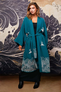 Model wears belted teal kimono style robe with ivory embroidery over long black dress