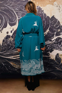 Model shows back of belted teal kimono style robe with ivory origami heron and Japanese wave embroidery