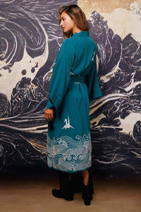 Model shows side of belted teal kimono style robe with ivory origami heron and Japanese wave embroidery