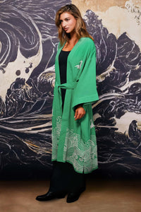 Model shows side of belted green kimono style robe with ivory origami heron and Japanese wave embroidery