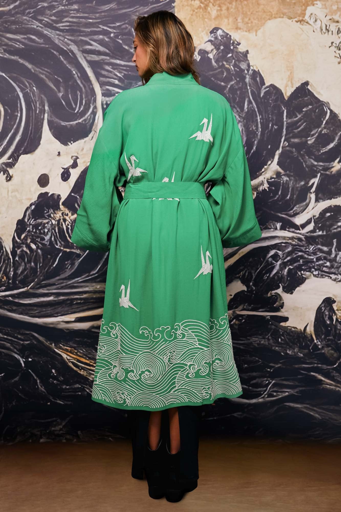 Model shows back of belted green kimono style robe with ivory origami heron and Japanese wave embroidery