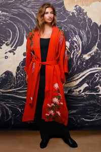 Model wears belted terracotta kimono style robe with wisteria and chrysanthemum embroidery over long black dress