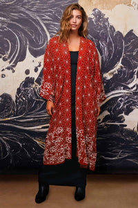 Model wears terracotta kimono style robe with ivory embroidery open over long black dress