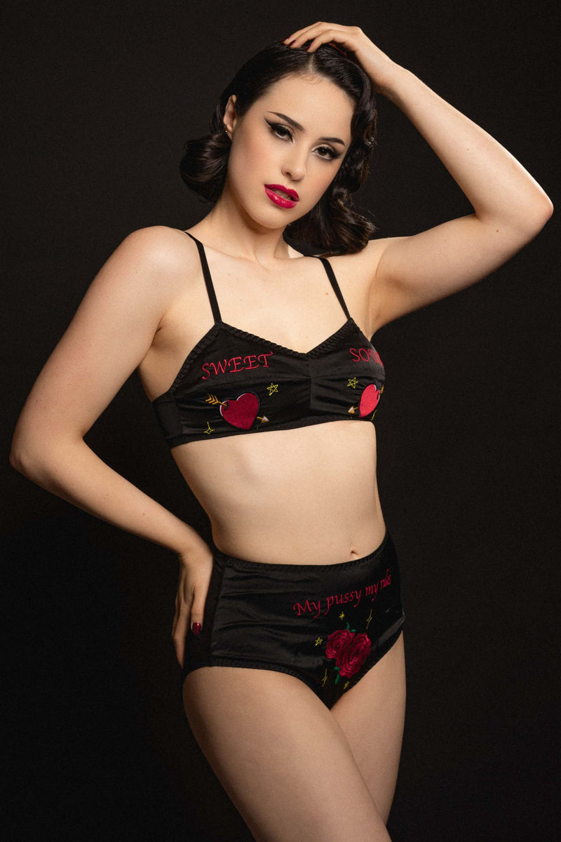 vintage model wears black satin bralette and high-waisted briefs with retro embroidery