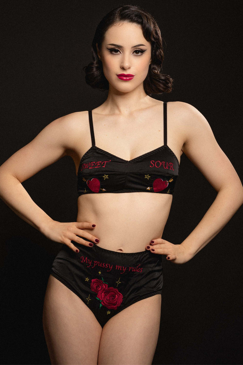 vintage model wears black satin bralette and high-waisted briefs with retro embroidery