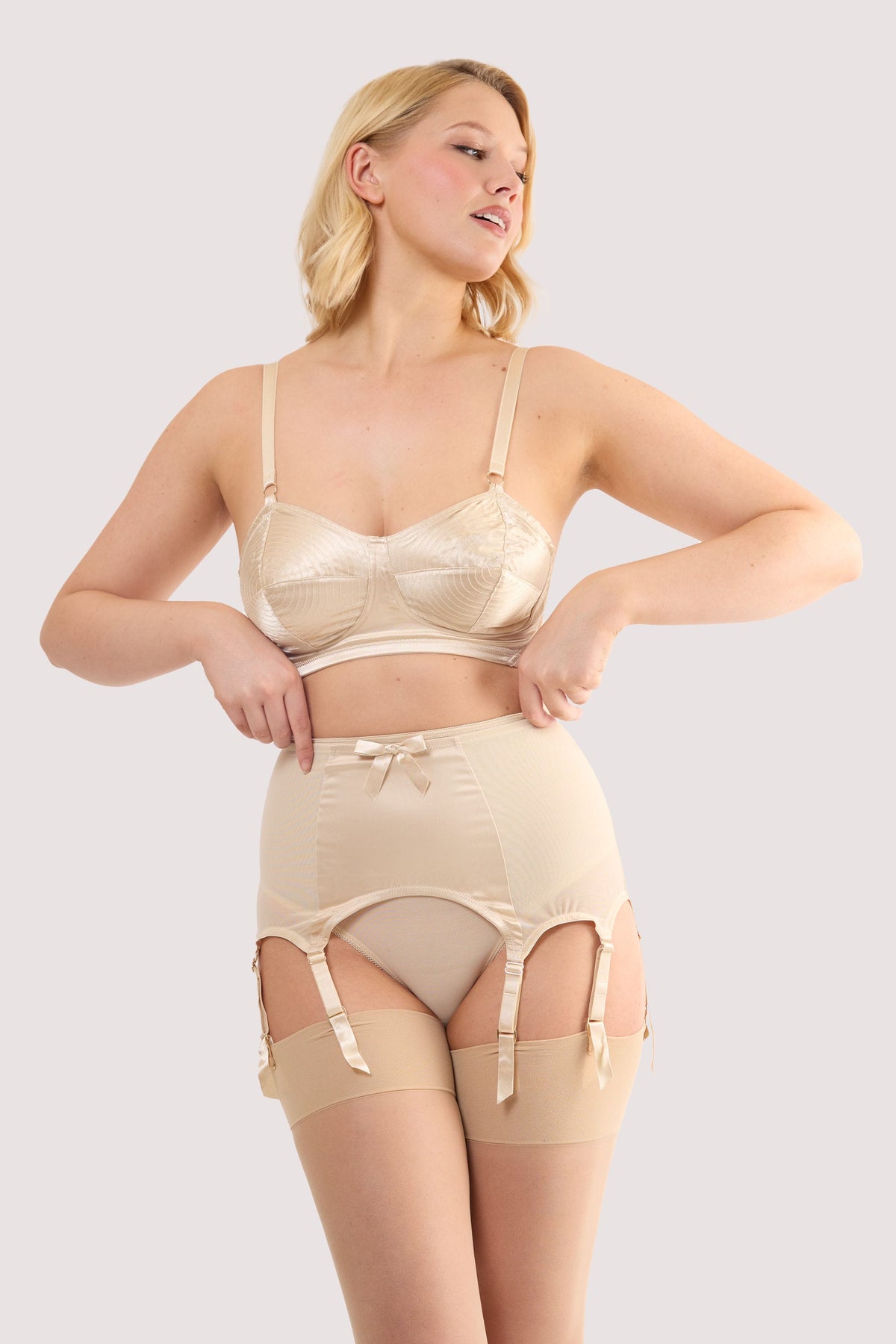 Model wears a champagne satin 8 strap retro everyday suspender with eight adjustable straps, soft and smooth finish with a matching brief and bra.