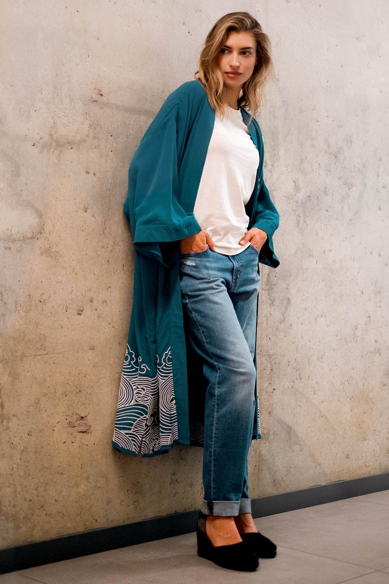 Model styles teal kimono robe embroidered with ivory herons and Japanese waves over jeans and a white t-shirt