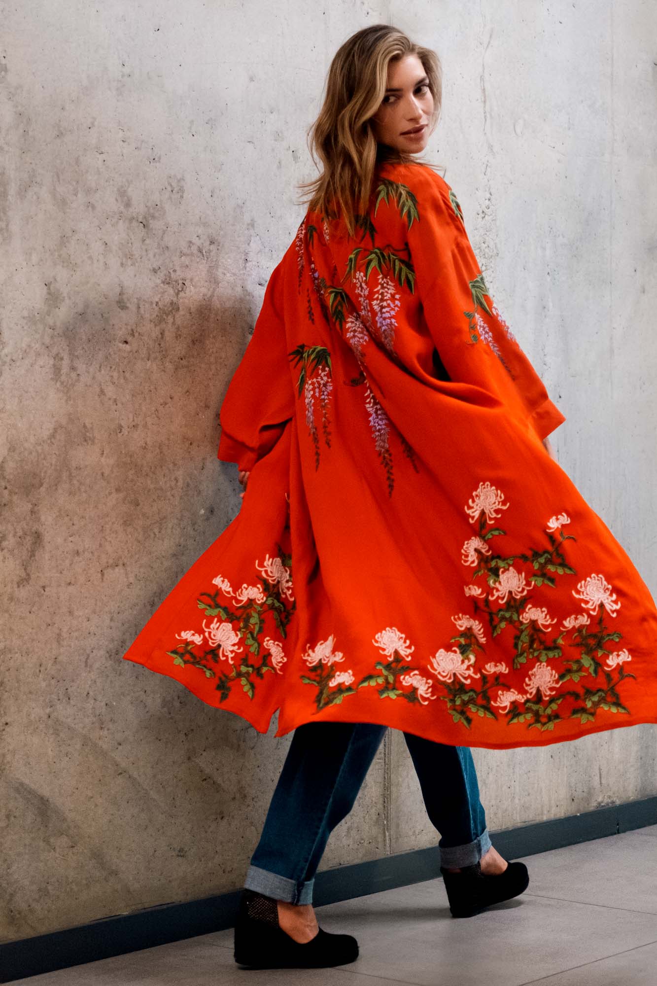 Model styles terracotta kimono robe embroidered with colourful wisteria and chrysanthemums over denim shorts and a black t-shirt