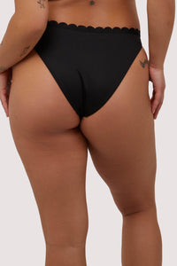 Model shows full brief back of sexy black scalloped bikini bottoms