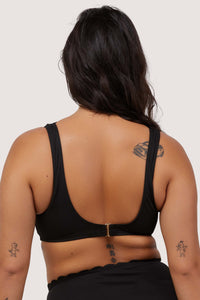 model shows hook and eye fastening back of black scalloped bikini top with thick straps