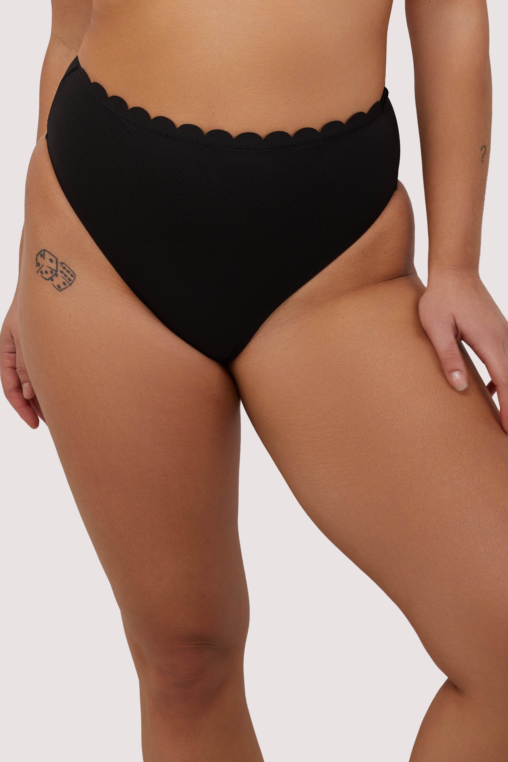 model wears black scalloped high waist bikini bottoms