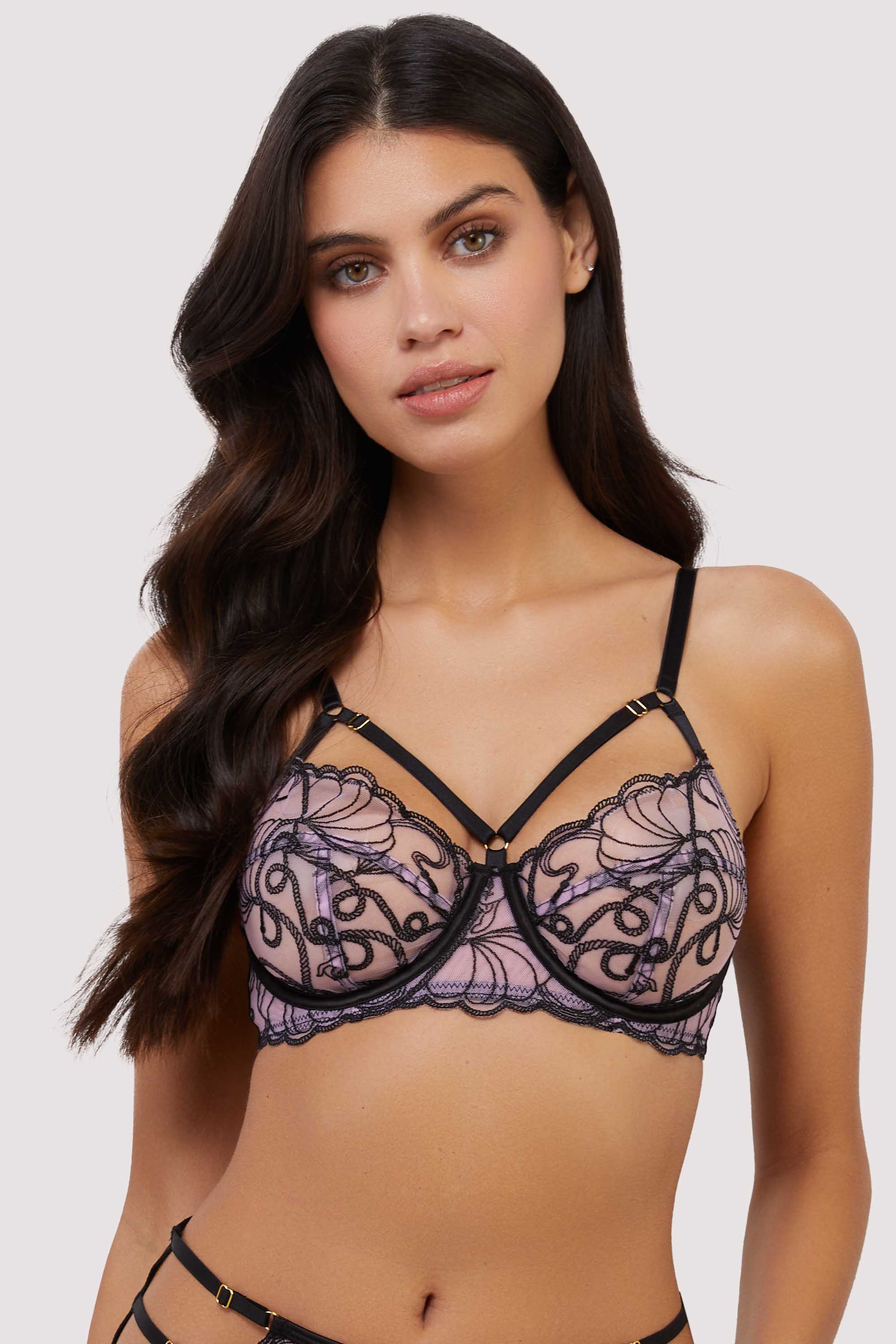 model wears pink and black embroidered bra with straps