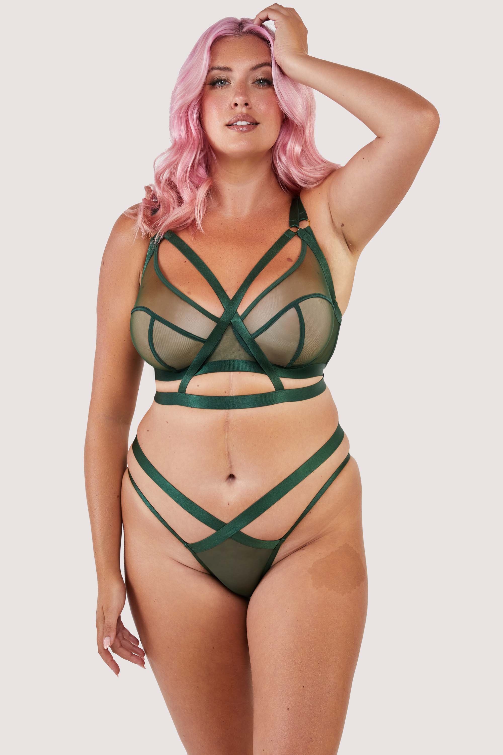 Green satin harness style bra seen with matching brief and suspender.