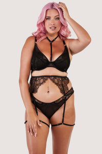 Black lacy suspender belt with gold hardware worn with matching bra and brief.