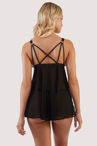 Back view of a black babydoll dress with art deco style cups, cage detailing on the bust and a clasp between the cups, with criss-cross straps at the back.