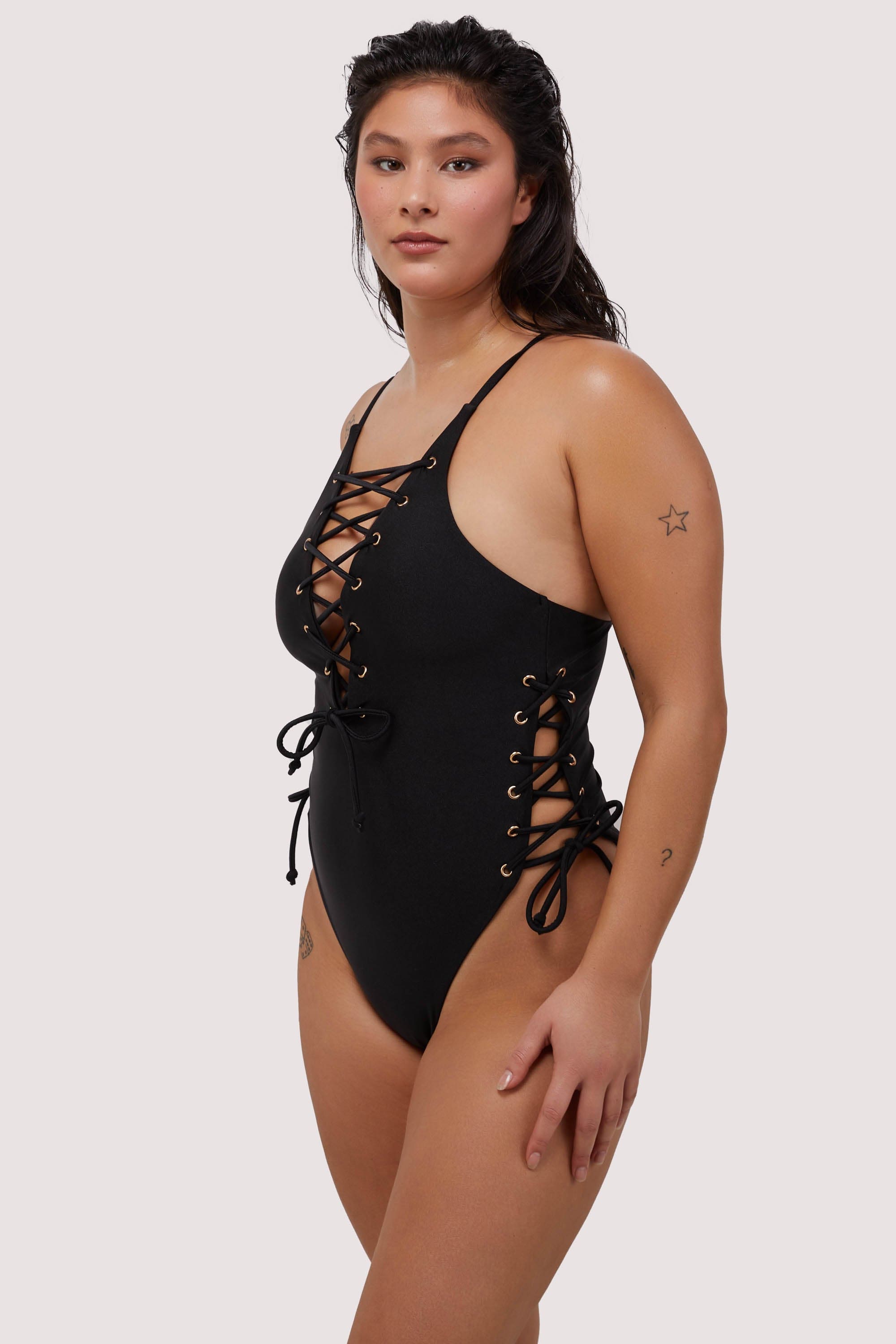 Model shows lace-up side to black plunge swimsuit