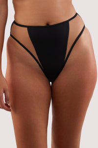 model wears black high-waist and high-leg bikini bottoms with nude mesh panels