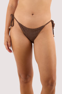 Model Wearing bronze sparkle bikini bottoms with adjustable ties and low-rise fit