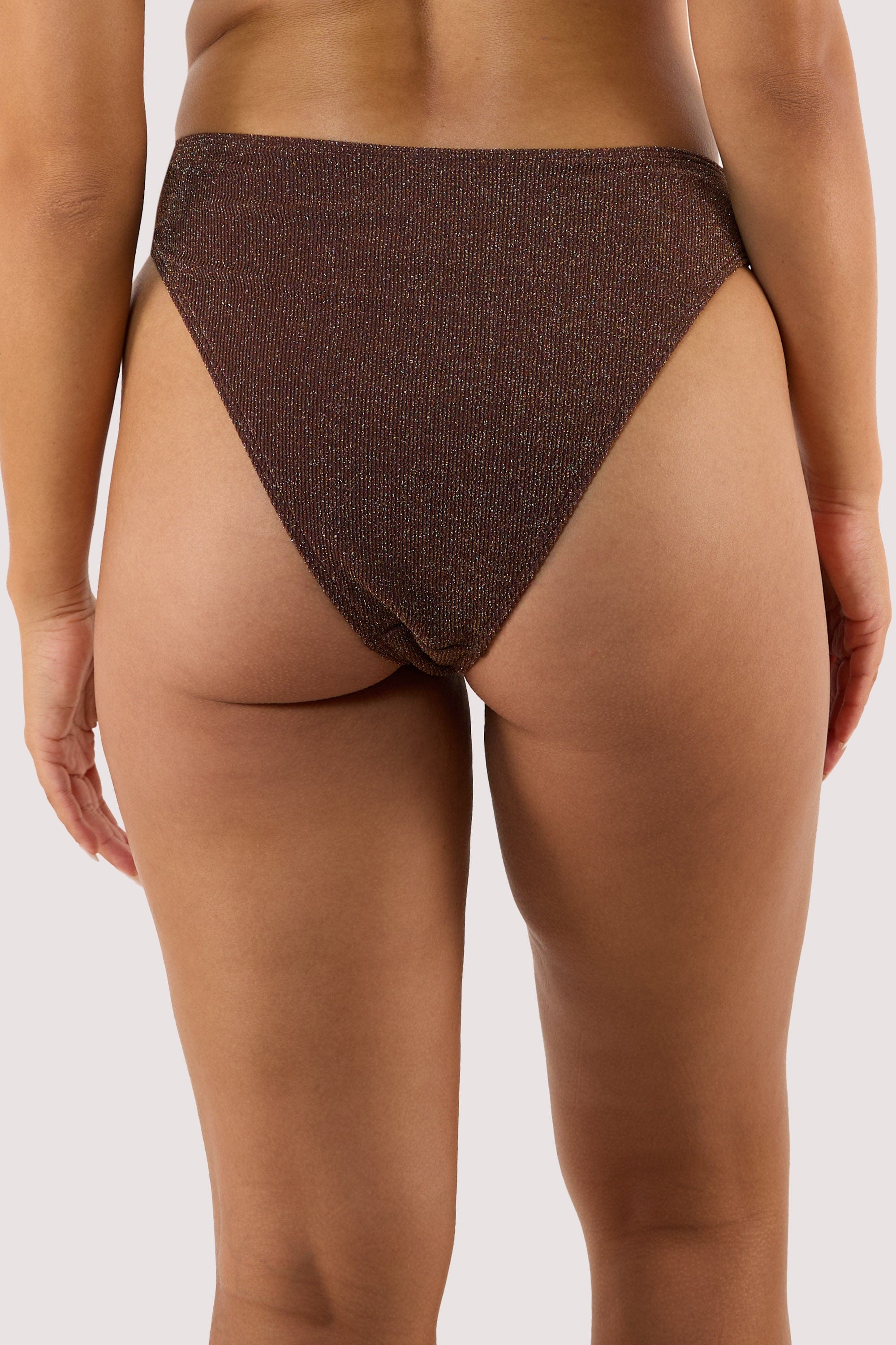 Model Back view of high-leg bikini bottoms in shimmering bronze fabric with a cheeky cut