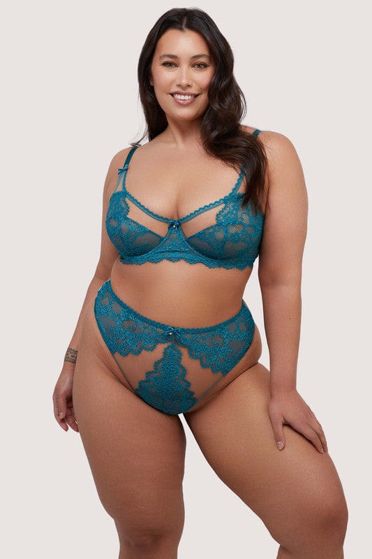 Model wears a teal eyelash lace high waist thong with velvet bow with pearl charm and nude mesh with teal eyelash lace panels, with a matching balconette bra.