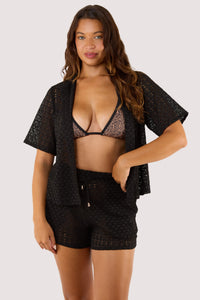 Model Wearing a black swimsuit and shorts, complemented by a relaxed-fit black crochet beach shirt with a button-down design.