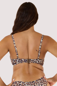 Model Back view with long brown hair wearing a leopard print bikini with adjustable straps, standing with hands on hips.
